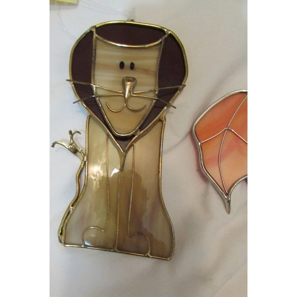 Stained glass leaves and lion handmade ornaments hang in window